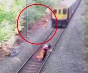 VIDEO INCREDIBIL! Un muncitor se arunca in fata trenului si salveaza un biciclist beat! Imaginile sunt...
